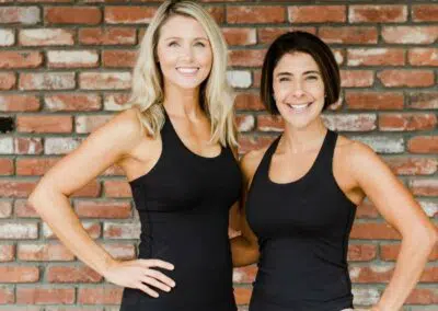 Two women team members in front of brick wall