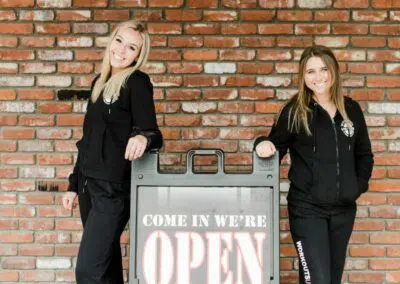 Two women, gym team members and open sign